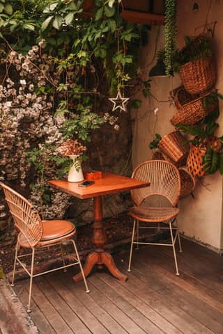 Warm outdoor café setting with wicker chairs and floral accents.