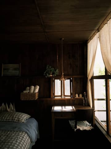 A warm, rustic bedroom with natural light streaming through the curtains.