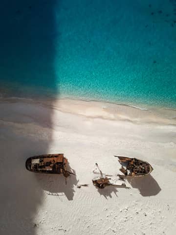 A couple of boats sitting on top of a sandy beach