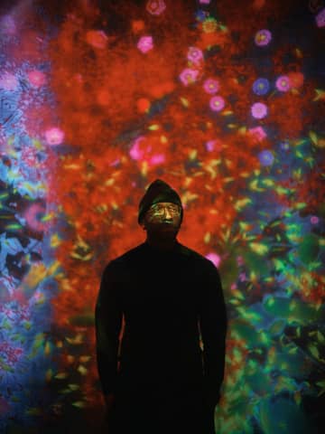 A person silhouetted by colorful projections.