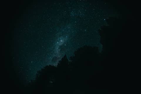 Night sky filled with stars and silhouettes.