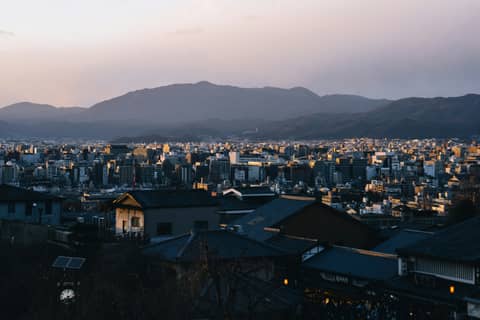 Cityscape at dusk, with mountains in background.
