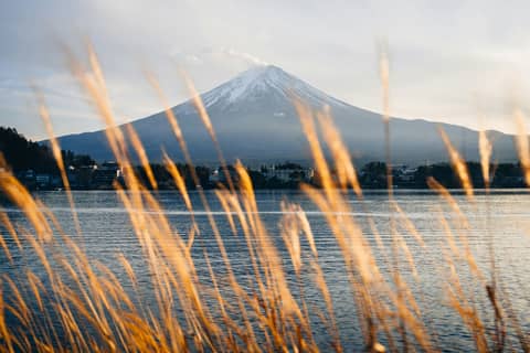Mount fuji overlooks a peaceful lake at sunset.