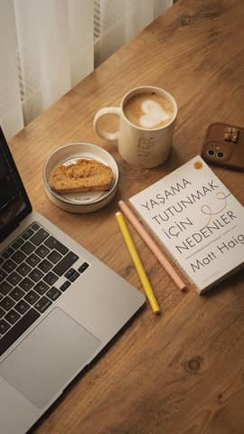 A warm-toned workspace featuring a laptop, coffee, and a book on a wooden desk, ideal for productivity.