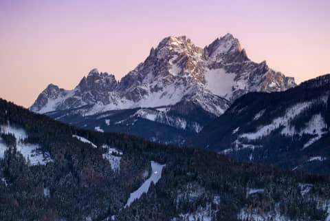 Snow-capped mountains peak against a colorful sunset.