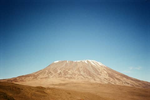 A mountain stands tall under a bright blue sky.