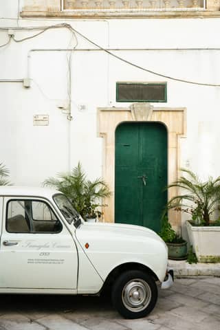 White car parked in front of a green door.