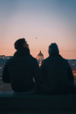 Two people watch the sunset over rome.