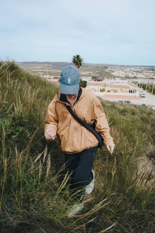 A person hikes up a grassy hill.