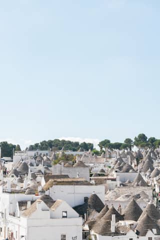 Cone-shaped houses cluster under a bright blue sky.