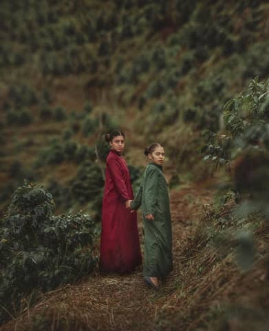 Two sisters in colorful dresses explore lush hills of Tingo María, Perú.