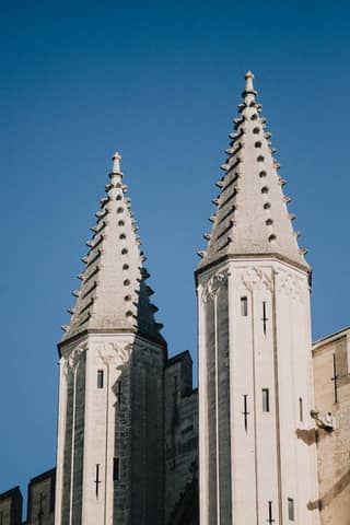 Close-up of the Gothic spires of Saint-Pierre Cathedral in Avignon, France against a clear blue sky.