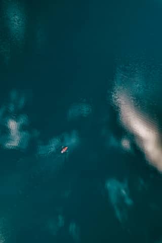 A person paddles a kayak on the tranquil water.